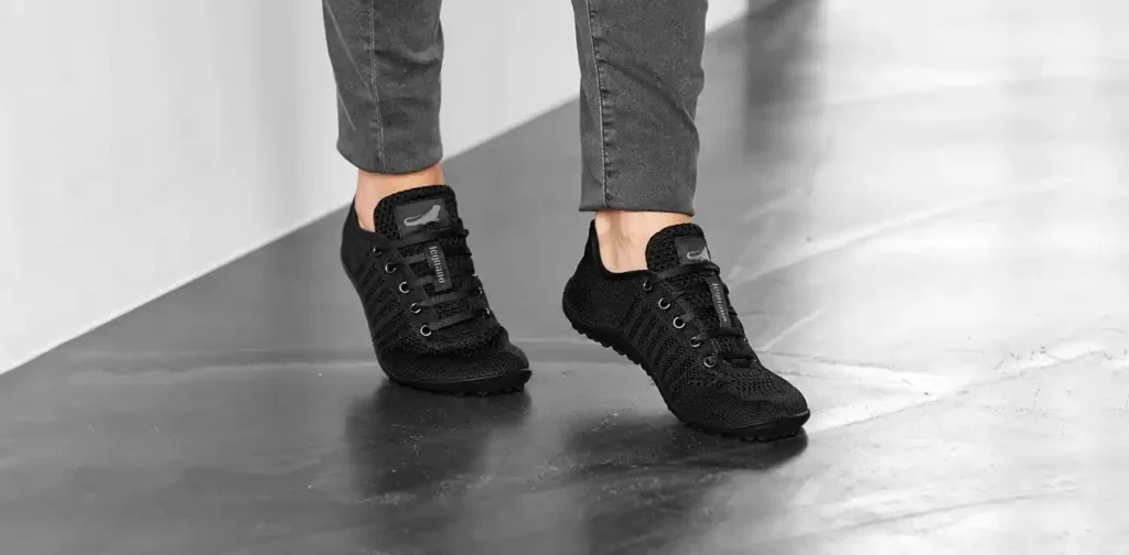 Eine Junge Frau testet ihre neu erworbenen leguano go Barfußschuhen indem sie sportliche Bewegungen macht.